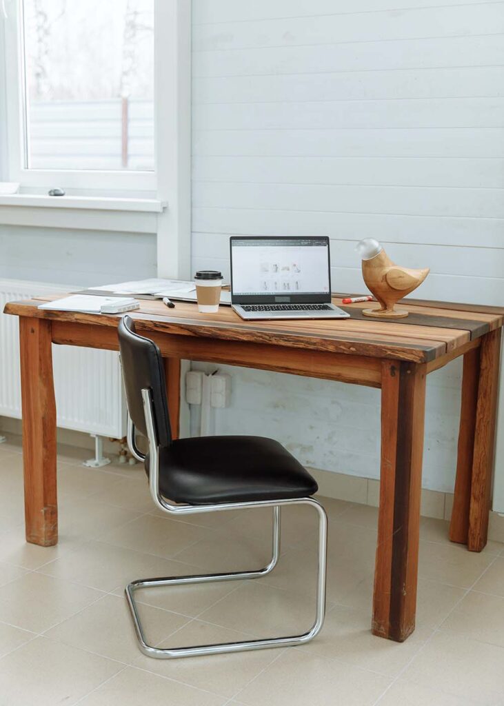 Laptop on top of a wooden desk in a white room